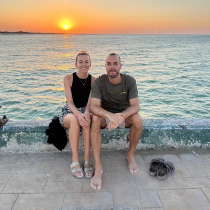 Bianca und Alex sitzen bei Sonnenuntergang auf der Hafenmauer einer Local Island