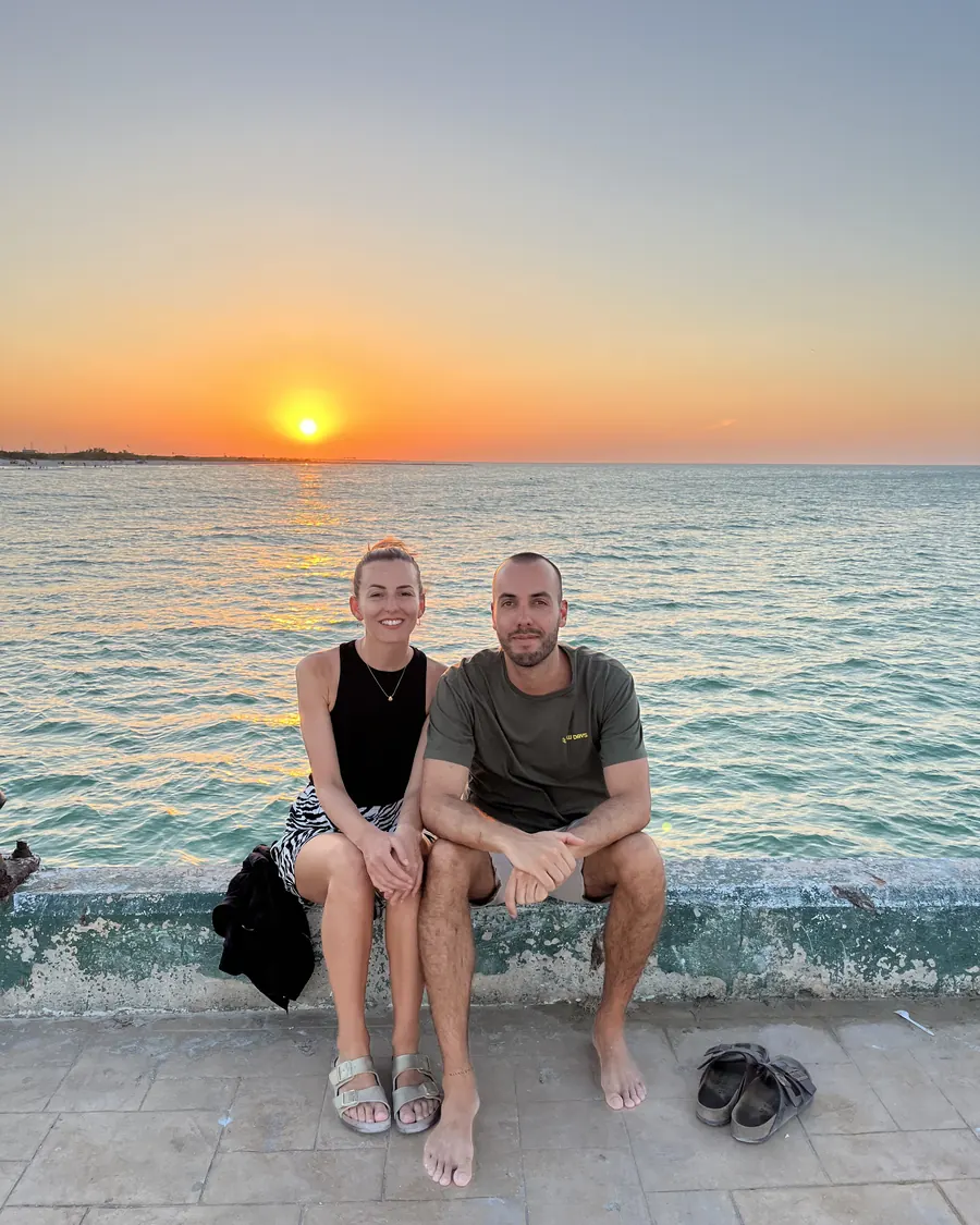 Bianca und Alex sitzen bei Sonnenuntergang auf der Hafenmauer einer Local Island